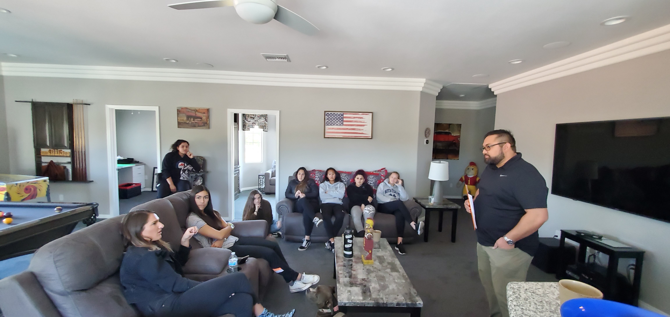 Dr. Jason von Stietz stands in a living room filled with female soccer players and discusses sport psychology